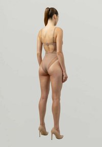 Lichtbruin badpak met dunne bandjes en een uitsnede op de rug; gladde textuur; gecombineerd met beige hoge hakken.
