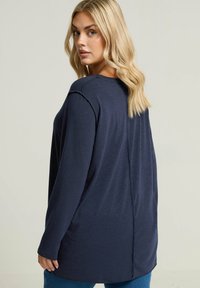 Marineblaues Langarmshirt mit entspannter Passform, rundem Ausschnitt und Rückennahtdetails, aus einem weichen, strukturierten Stoff gefertigt.