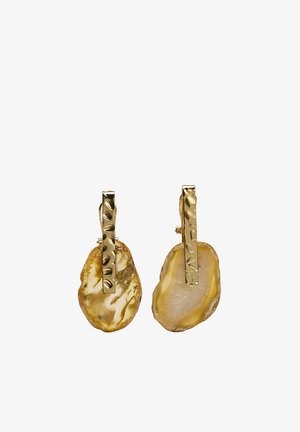 Złocone teksturowane kolczyki w kształcie pręta z nieregularnymi kroplami z bursztynowej żywicy, na klipsy, na białym tle.