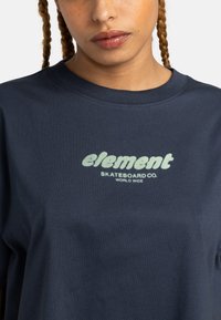 Navy blue cotton t-shirt featuring a light green graphic text logo reading “element SKATEBOARD CO. WORLD WIDE” centered on the chest.
