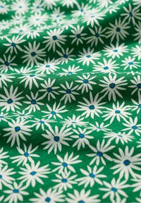 Tessuto verde con un motivo di margherite bianche con centri blu, caratterizzato da una texture liscia e un aspetto fluente.
