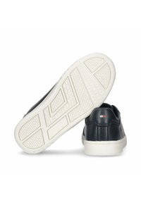Sneaker in pelle nera con suole in gomma bianca, motivi testurizzati e accenti con logo sul tallone. Vista posteriore che mostra la forma curva della scarpa.