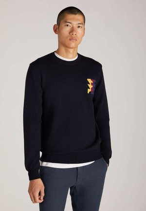 Pullover navy in maglia con collo a girocotto ribbed, caratterizzato da un motivo zigzag multicolore sul lato sinistro del petto. Texture morbida, vestibilità regolare.