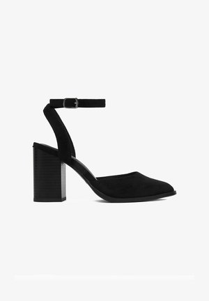 Zapato de tacón ancho para mujer de ante negro con correa en el tobillo y hebilla plateada, punta cerrada, tacón de altura media, vista lateral sobre fondo blanco.