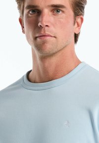 Lichtblauwe korte mouwen crew neck sweatshirt met een gestructureerde stof en een klein geborduurd pinguïnlogo op de linkerborst.