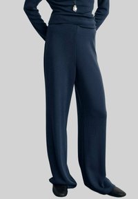 Pantaloni largi, de culoare albastru închis, dintr-un material moale și texturat, cu talie înaltă, având cusături minime și un finisaj neted.