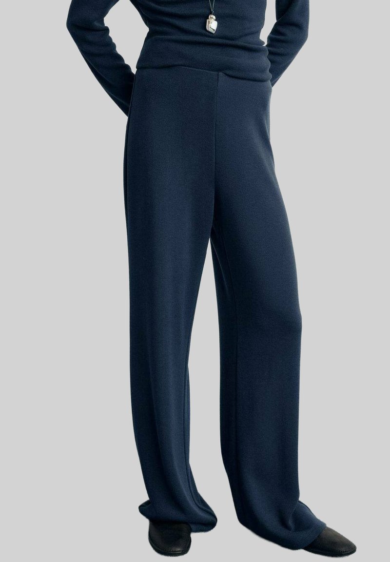 Pantaloni largi, de culoare albastru închis, dintr-un material moale și texturat, cu talie înaltă, având cusături minime și un finisaj neted.