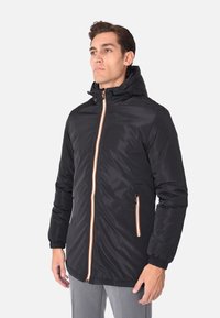 Giacca nera con cappuccio e zip frontale, caratterizzata da dettagli arancioni. Include due tasche laterali e polsini elasticizzati per una vestibilità aderente.