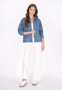 Ljust blå jeansjacka med knapprad fram, bröstfickor och detaljer med elastiska ärmslut. Matchas med vita vida byxor och sneakers.