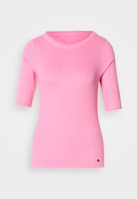 Roze slim-fit shirt met korte mouwen en een ronde halslijn, met een klein zwart logo nabij de onderzoom op een lichtgrijze achtergrond.