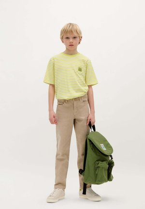 Geel en wit gestreept t-shirt, beige broek en een groene rugzak met voorzakken. Lichtgekleurde sneakers. Eenvoudig, casual ontwerp.