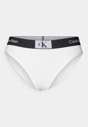 Culotte blanche femme Calvin Klein avec une taille élastique noire portant le logo, un design épuré et une texture de tissu lisse.