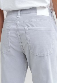  Lichtgrijze katoenen broek met een ontwerp van voor- en achterzakken, een soepele textuur en een wit label op de tailleband.