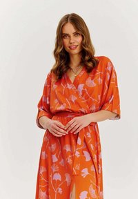 Oranžové šaty s růžovým vzorem ginkgo listu, zavinovací design, výstřih do V, krátké rukávy a stahovaci pas, s bočním rozparkem pro snadný pohyb.