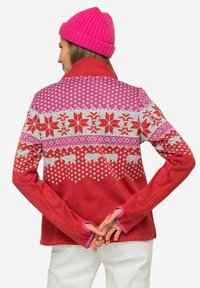 Pullover in pile rosso con motivi geometrici fucsia e argentati, caratterizzato da motivi di orsi polari e aperture per il pollice nelle maniche.