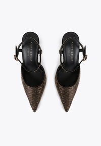 Decolletè nere a punta con cinturini slingback, decorati con borchie dorate e fibbie, marchiate Kurt Geiger London sulla soletta.