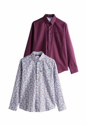 Two long-sleeve shirts: one solid burgundy with a pocket, one patterned in small multicolored floral design on a light background.