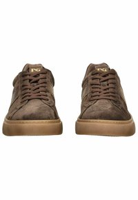 Brown suede sneakers featuring a round toe, flat gum sole, lace-up detail, and subtle branding on the tongue. Textured upper surface.