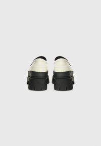 Chaussures à plateforme noires épaisses avec un dessus en cuir blanc lisse. Présentent un bout rond et une semelle en caoutchouc texturée.