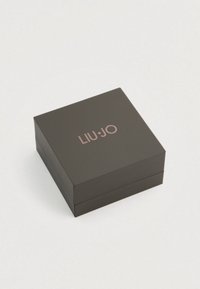 Melnas kvadrātveida dāvanu kaste ar gludu tekstūru un vāku, uz kura ir iegravēts zīmola nosaukums "LIU•JO" rozā zelta krāsā.