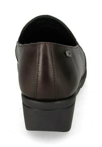 Scarpa in pelle marrone con tacco nero basso e spesso. Texture liscia, forma arrotondata e un piccolo dettaglio metallico sul lato.