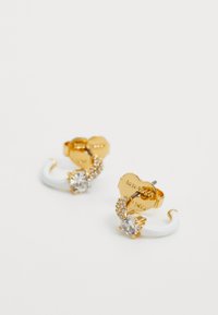 Orecchini a cerchio dorati con accenti bianchi, cristalli trasparenti e dettagli intricati. Texture metalliche e pietrose lisce con un leggero luccichio.