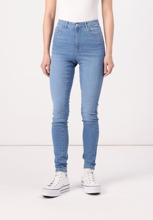 Svijetloplave skinny traperice visokog struka s diskretnim šavovima, bočnim džepovima i glatkom traper teksturom, uparene s bijelim visoko-top adidasicama.