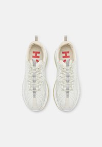 Valkoiset urheilujalkineet, joissa on teksturoitu päällinen, hopeiset yksityiskohdat ja punainen logo sisäpohjassa. Varustettu nauhakiristyksellä ja lenkkikannalla.