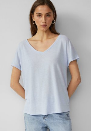 T-shirt bleu clair en V en tissu doux avec des manches courtes et une coupe décontractée. Détail de couture notable à l'ourlet et sur le côté.