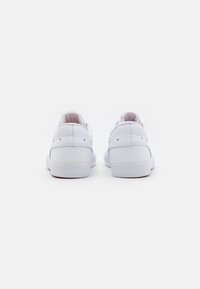 Baskets en cuir blanc avec une finition lisse, un col rembourré et un design minimaliste comprenant de légères perforations sur les côtés.