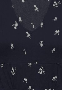 Robe bleu marine foncé avec un décolleté en V et un petit imprimé floral blanc dispersé, avec une couture à la taille.