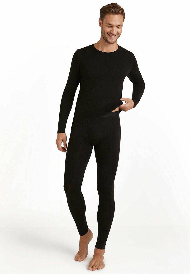 Zwarte thermische lange mouw top en strakkere legging gemaakt van zachte stof. Het ontwerp heeft een ronde hals en een gladde textuur met minimale naden.