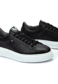 Sneaker in pelle nera con punta tonda, design con lacci, suola in gomma bianca e discreto logo metallico sul lato.