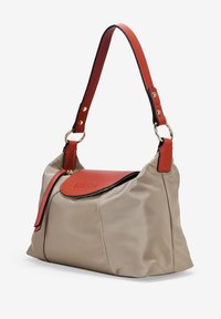 Bolso de nylon beige con una solapa de cuero rojo y ribete negro. Cuenta con una correa sencilla con herrajes dorados y una forma redondeada.