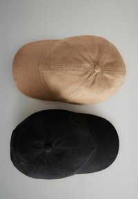 Due cappelli da baseball impilati: uno di colore beige, in tessuto testurizzato, e uno nero, in tessuto liscio. Entrambi presentano una corona arrotondata e una visiera curva.