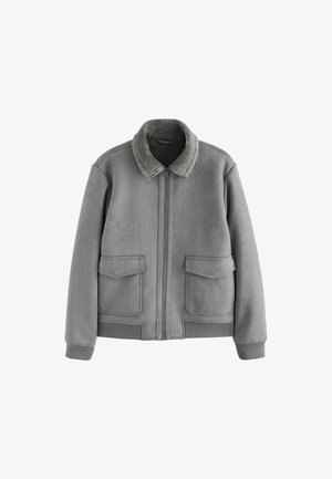 Veste en suède grise avec un col en fourrure, fermeture éclair, deux poches plaquées devant, poignets et ourlet côtelés. Texture lisse avec une finition douce.
