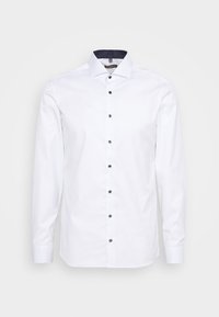 Camicia bianca a maniche lunghe con colletto aperto, colletto interno blu navy e bottoni scuri lungo il davanti, realizzata in morbido tessuto di cotone.