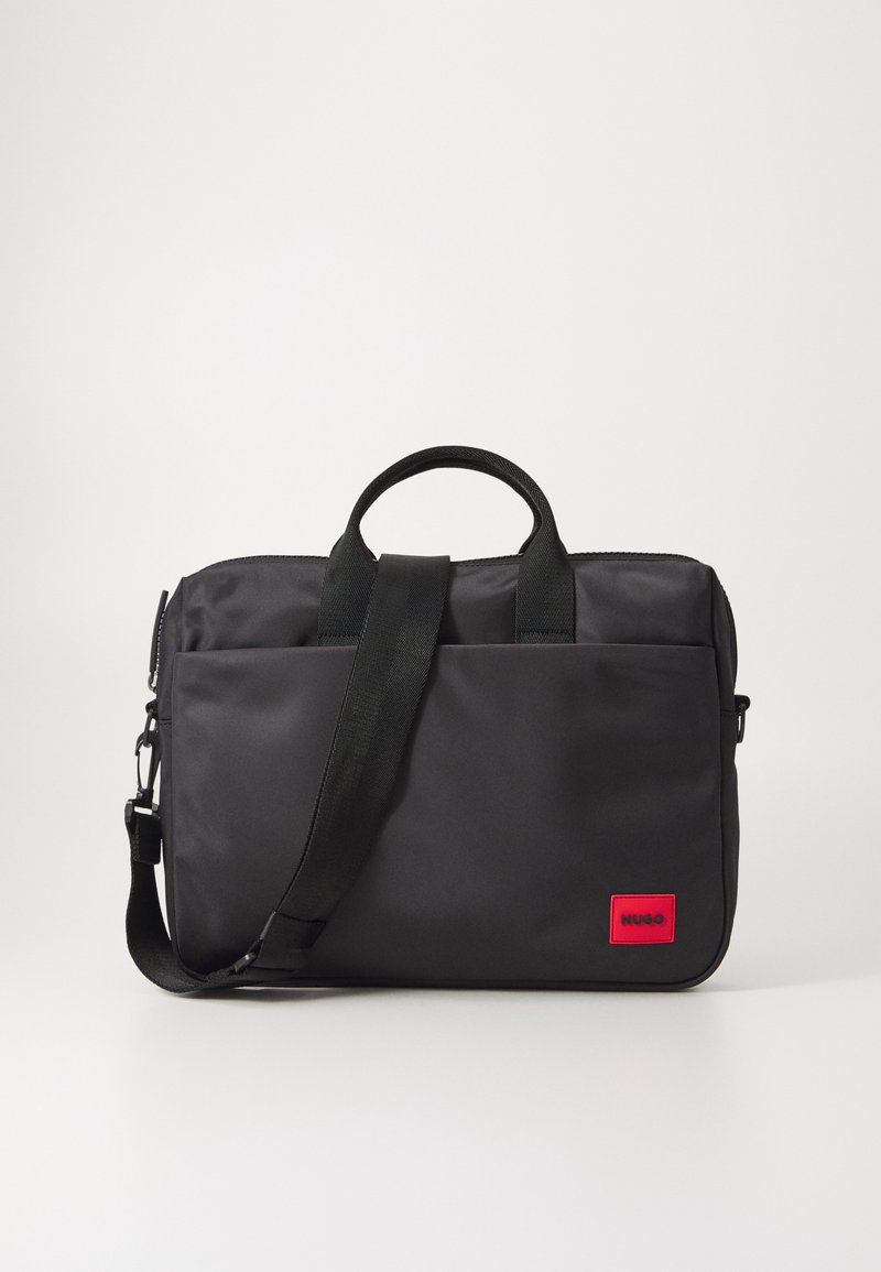 Svart bæreveske for bærbar datamaskin laget av glatt nylon, med dobbel håndtak, avtakbar skulderrem og et rødt logo-patch foran.
