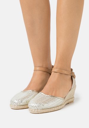 Srebrne sandały na koturnie z teksturowaną powierzchnią, okrągłym noskiem, paskiem na kostkę i plecioną podeszwą z juty. Błyszczące wykończenie i subtelny wzór na górnym materiale.