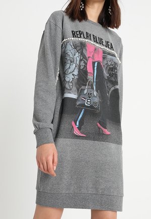 Robe sweat gris présentant une image imprimée d'une personne portant des talons roses et un sac à main élégant, rehaussée de détails en perles au niveau du col.