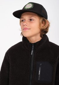 Mustat fleece-takkia, jossa on korkea kaulus, teksturoitu kangas, sivuvetoketju ja rintatasku. Varusteena musta lippis, jossa on värikäs logo.