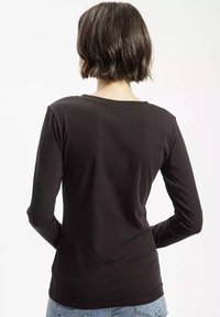 Czarna bawełniana koszula z długim rękawem, okrągłym dekoltem, gładką fakturą, dopasowanymi rękawami i zaokrąglonym dołem, przedstawiona z tyłu.