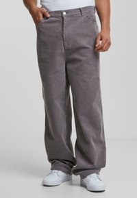 Grijze corduroy wijde broek met zichtbare textuur, vijf-pocket ontwerp en een knoopsluiting. Gecombineerd met witte sneakers.