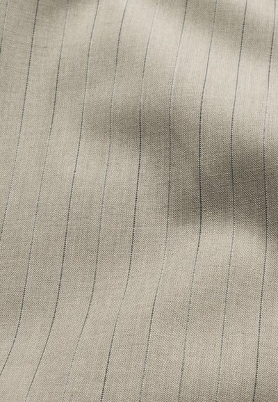 Μπεζ ύφασμα με λεπτές, ομοιόμορφα τοποθετημένες κάθετες σκοτεινές ρίγες και διακριτικά υφή υφανσίματος.