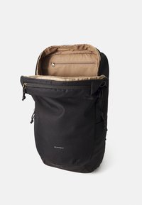 Zaino nero con interni beige, dotato di un compartimento con zip, spallacci regolabili e un logo discreto sul davanti. Tessuto resistente.