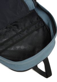 Interno dello zaino in tessuto blu e nero. Presenta tasche in rete e una fodera nera liscia con un motivo geometrico. Apertura con zip nella parte superiore.