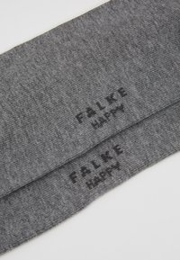 Grå stof med en tekstureret vævning. To mærker med "FALKE" og "HAPPY" trykt i sort. Flad form, blød finish.