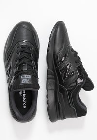 Ein Paar schwarze New Balance 997H Sneaker aus gemischten Materialien mit Mesh- und Lederdetails, die von oben und von der Seite auf einem weißen Hintergrund gezeigt werden.