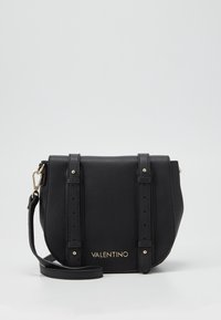 Borsa a tracolla in pelle nera con hardware dorato, due cinturini decorativi e logo dorato sul fronte. Silhouette compatta e arrotondata.