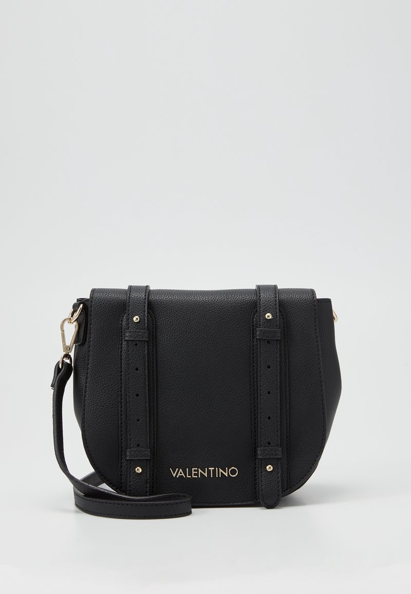 Borsa a tracolla in pelle nera con hardware dorato, due cinturini decorativi e logo dorato sul fronte. Silhouette compatta e arrotondata.